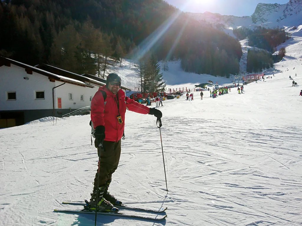 Skifahrer in roter Jacke breitet die Arme aus.